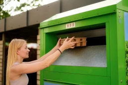 Femeie aruncand cartoane la containerul de reciclare